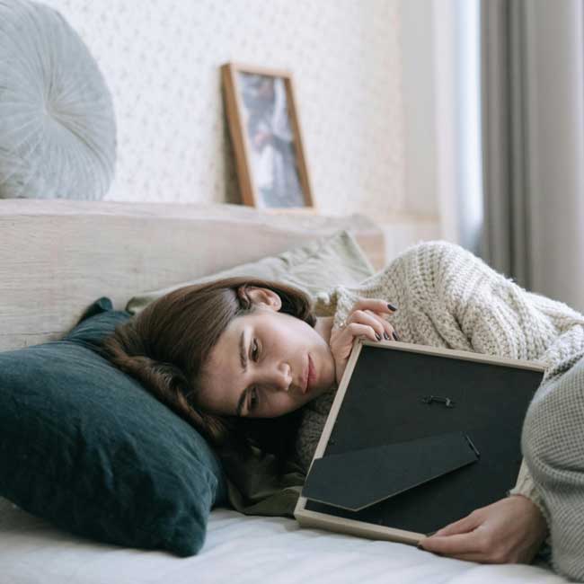 A sad woman lying down hugging a portrait